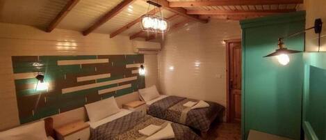 A room with two beds, wooden beams on the ceiling, and a green accent wall.
