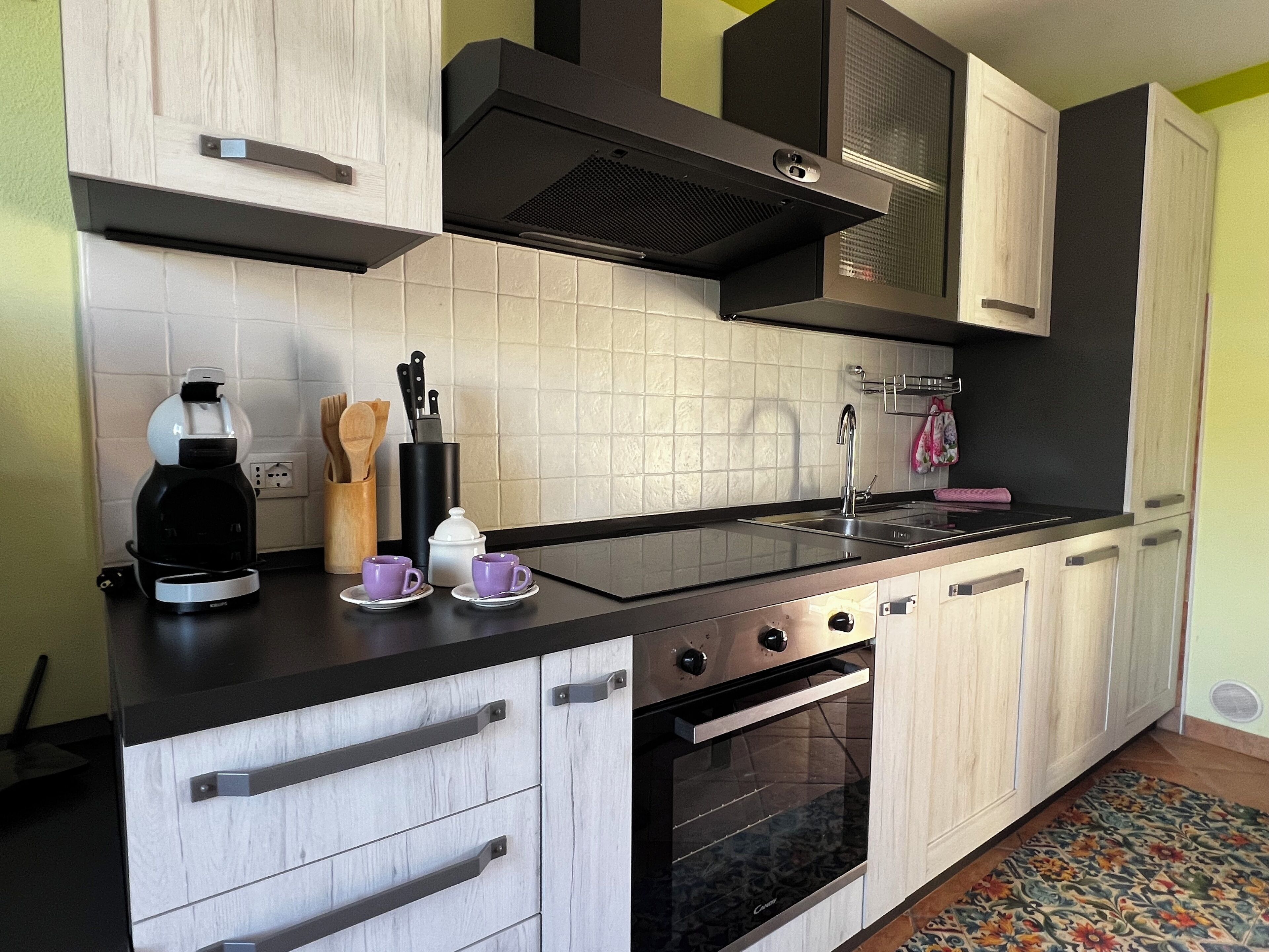 Une cuisine moderne avec un four noir, des armoires blanches et un pare-feu en carreaux.