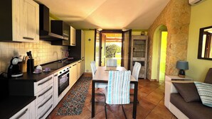 Una cocina compacta con comedor, pared de piedra y vistas al exterior.