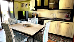 Una cocina con mesa, sillas, televisor y armarios.