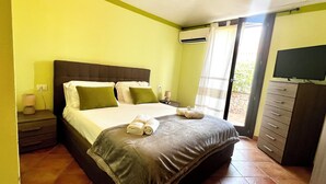Un dormitorio con cama, mesitas de noche, aire acondicionado, televisor y armario.