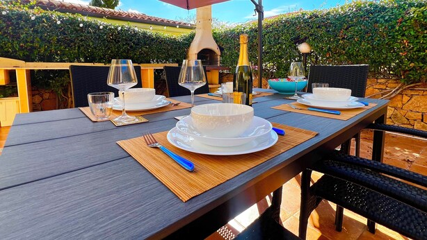 Un espacio al aire libre con mesa de madera preparada para dos personas, bajo un paraguas grande.