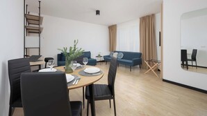 Ein modernes Wohnzimmer mit Essbereich, einer Treppe und einem großen Fenster mit Vorhängen.