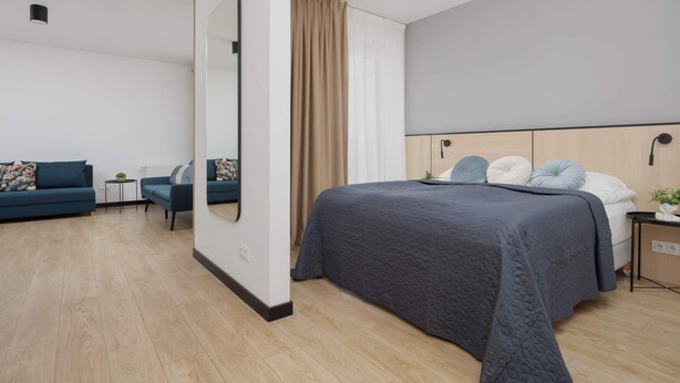 Ein modernes Hotelzimmer mit einem großen Bett, einer Couch, einem kleinen Tisch und einem Spiegel.