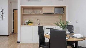 Eine moderne Küche mit weißen Schränken, einer Mikrowelle und einem Spülbecken. Es gibt einen Esstisch mit Stühlen und eine Vase mit Blumen.