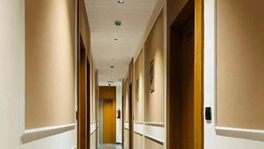 A hotel hallway with marble flooring, beige walls, and wooden doors. - HOTEL SAWARIYA (Ahmedabad)