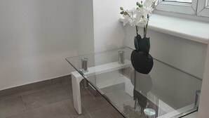 A modern room with a glass-top table, white walls, and a window. - Modern 2BR Apartment In Prime Vienna (Vienna)
