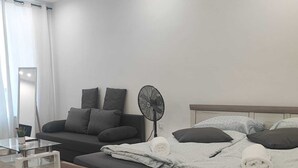 A modern bedroom with a bed, a bedside table, a fan, and a large mirror. - Modern 2BR Apartment In Prime Vienna (Vienna)