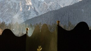Ein Gebirge mit schneebedeckten Gipfeln und im Vordergrund ein Zaun und Blumen.