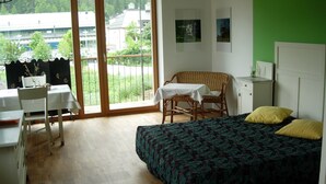 Ein Zimmer mit Bett, Stuhl, Tisch und Blick ins Freie.