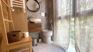 Un bagno con un mobile vanitario in legno, un lavandino bianco, un WC e una doccia.