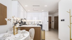 A modern kitchen with white cabinetry, a wooden island, and a dining area set for a meal. - Close to Community Park, Minutes Walk from Circle Mall, and Short Drive to Dubai Miracle Garden (Dubai)