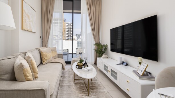 A modern living room with a sofa, coffee table, and TV. - Close to Community Park, Minutes Walk from Circle Mall, and Short Drive to Dubai Miracle Garden (Dubai)