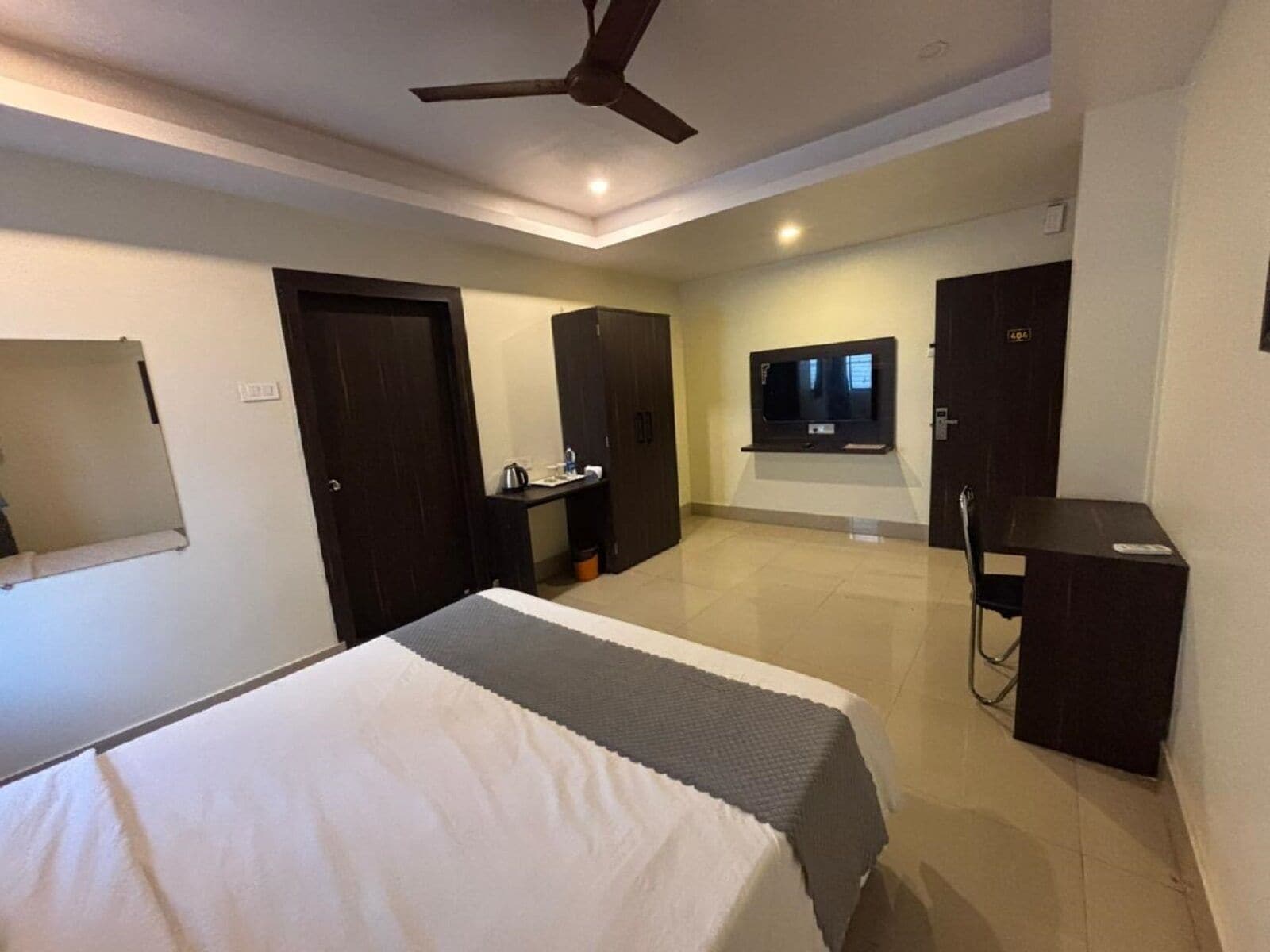 A hotel room with a bed, a desk, a TV, and a wardrobe.