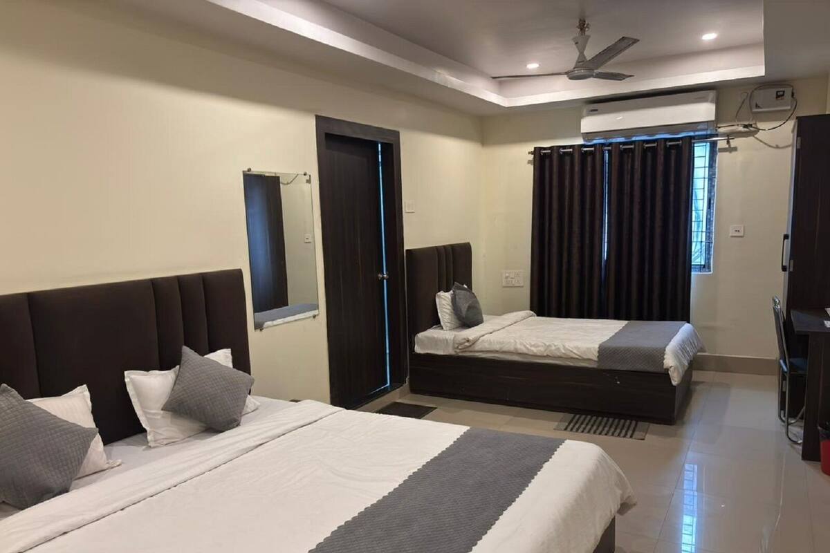 Une chambre d’hôtel avec deux lits, un ventilateur de plafond, un appareil de climatisation et une fenêtre avec des rideaux.