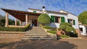 Una casa de dos pisos con una escalera de piedra que lleva a un porche de madera.