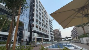 A modern hotel with a pool area, outdoor seating, and a large umbrella. - Azizi 505 Fully Furnished Apartment (Dubai)
