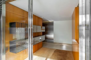 A modern interior with a glass partition, metal lockers, wooden paneling, and a tiled floor. - Pool, Terrace & Beach Vibes in Poblenou (Barcelona)