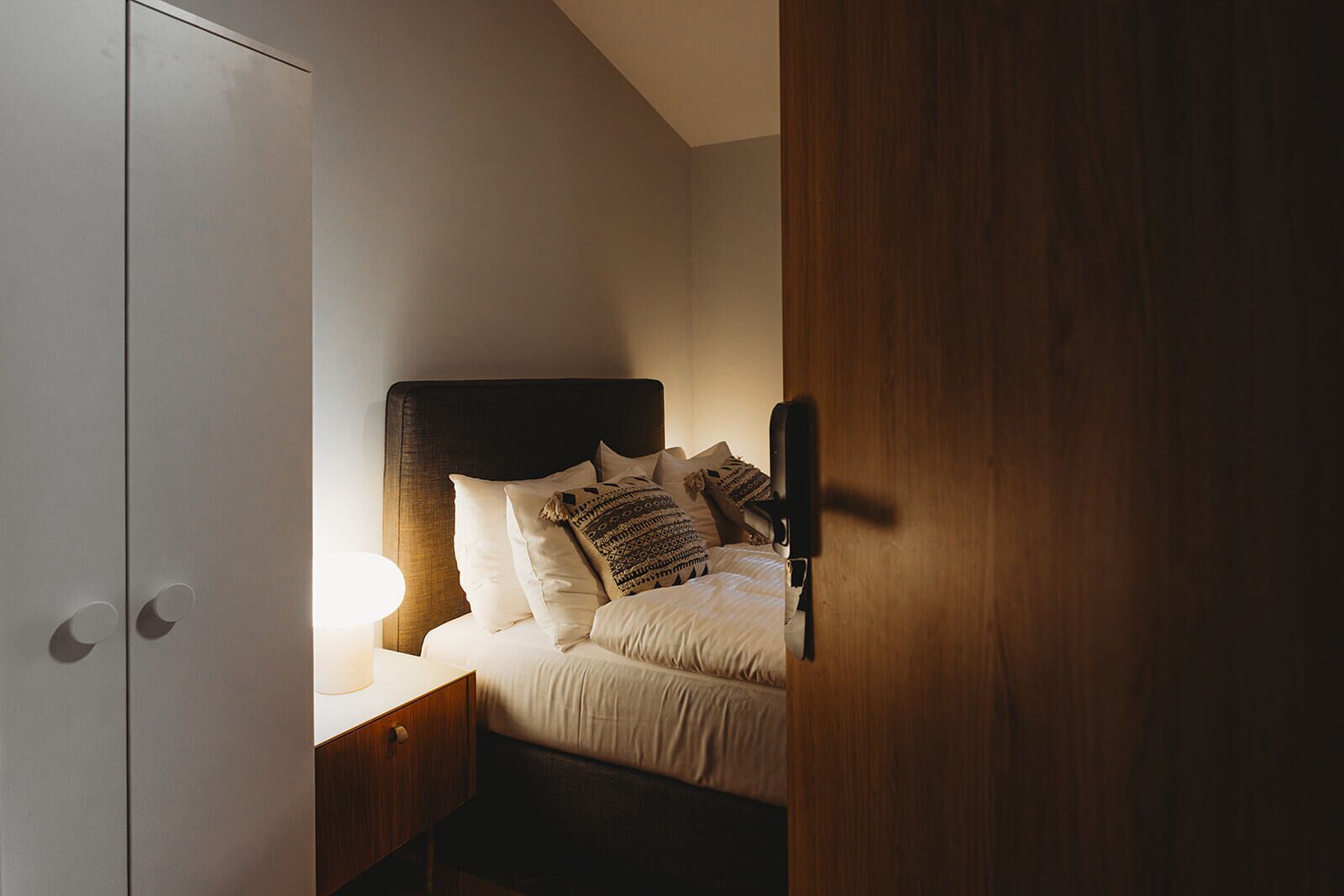 Un dormitorio con cama, mesita de noche y velador.