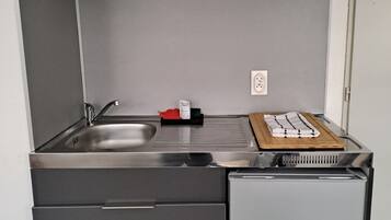 A compact kitchen with a microwave, sink, and storage drawers.