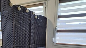 Een moderne woonkamer met een donkerblauwe bank, een houten bijzettafeltje met een zakdoosje, een kleine potplant en een kamerbreed tapijt met een patroon.