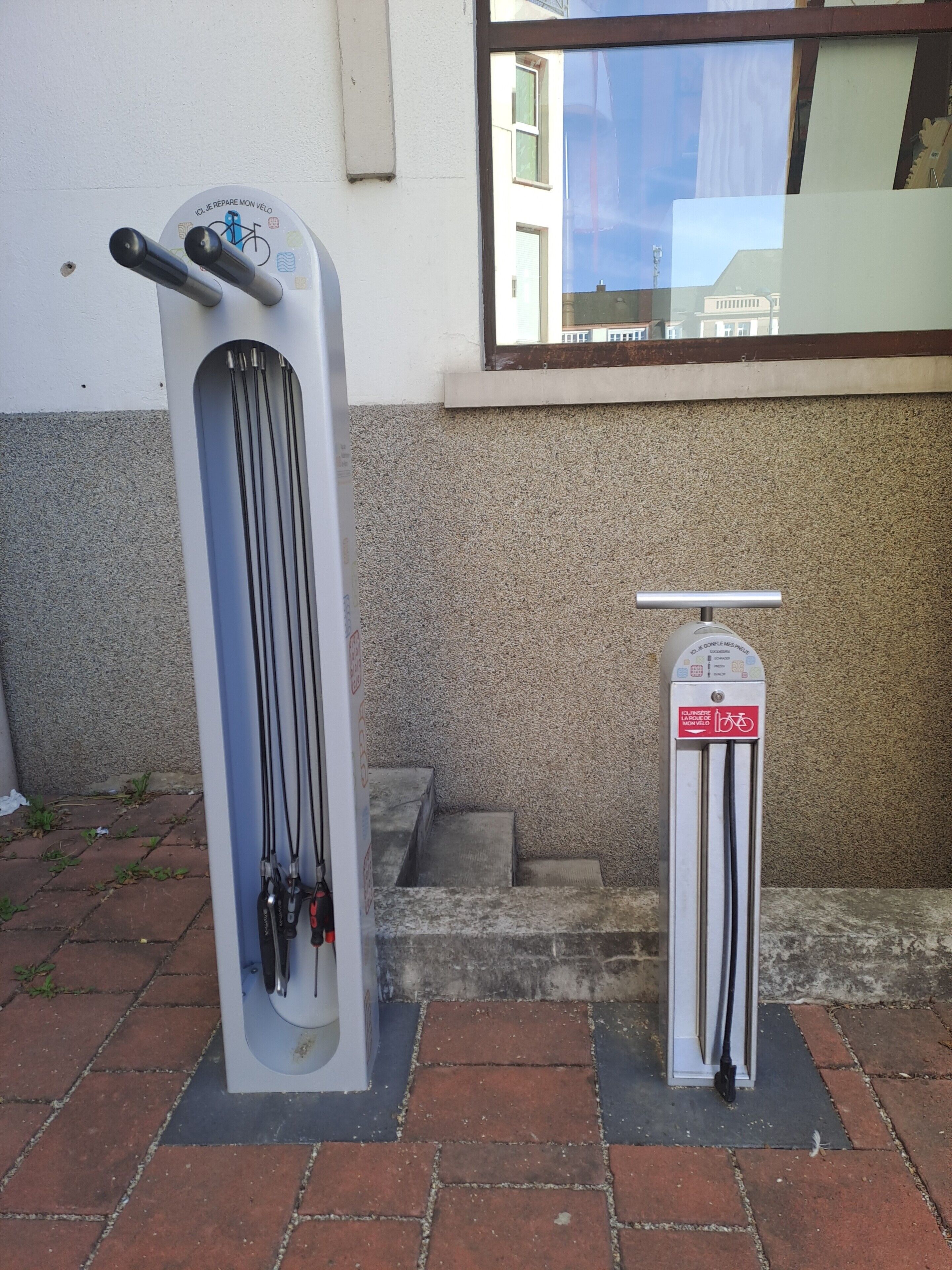 Un stationnement pour vélos équipé d’un support à vélos et d’un distributeur automatique de billets.