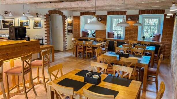 Un comedor amplio con mesas y sillas de madera, paredes de ladrillo y ventanas grandes.