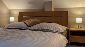 Ein Schlafzimmer mit einem Bett, zwei Nachttischlampen, einem Nachttisch und einem Kopfteil.