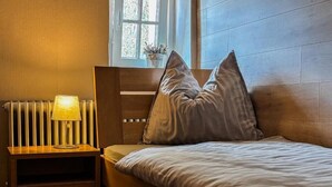 Un dormitorio con cabecera de madera, mesita de noche con lámpara y dos almohadas.