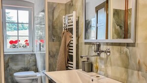 Un baño con lavamanos blanco, un espejo y un perchero para toallas.
