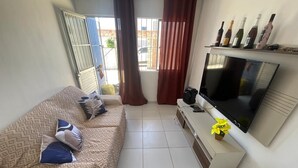 Una sala de estar moderna con un sofá, televisor y una pequeña mesa con una flor.