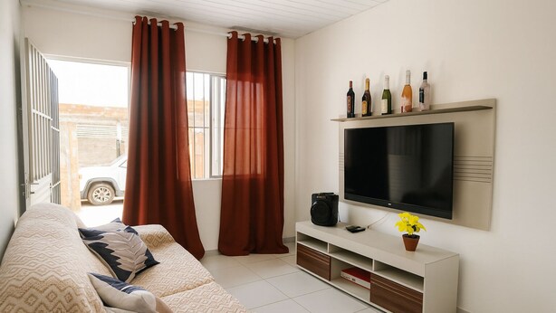 Una sala moderna con un sofá, televisor y botellas de vino en un estante.