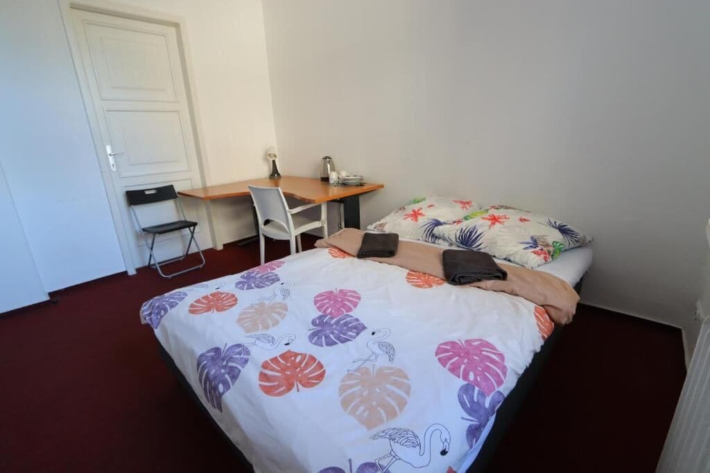 Une petite pièce propre et bien rangée, avec un lit, un bureau et une chaise.