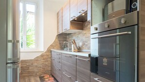 Une cuisine moderne dotée d’appareils électroménagers en acier inoxydable, de meubles en bois et d’une fenêtre laissant entrer la lumière naturelle.