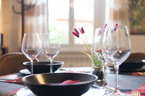 A dining table set with wine glasses, a black bowl, and a small vase with flowers. - Orlando apartment (Roma)