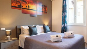 Une chambre d’hôtel avec un lit, des oreillers, une table de chevet, une lampe et des œuvres d’art accrochées au mur.