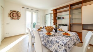 A dining area with a table set for two, featuring a blue and white patterned tablecloth, white chairs, and a basket of bread. - il giardino di Laura (Pompeiana)