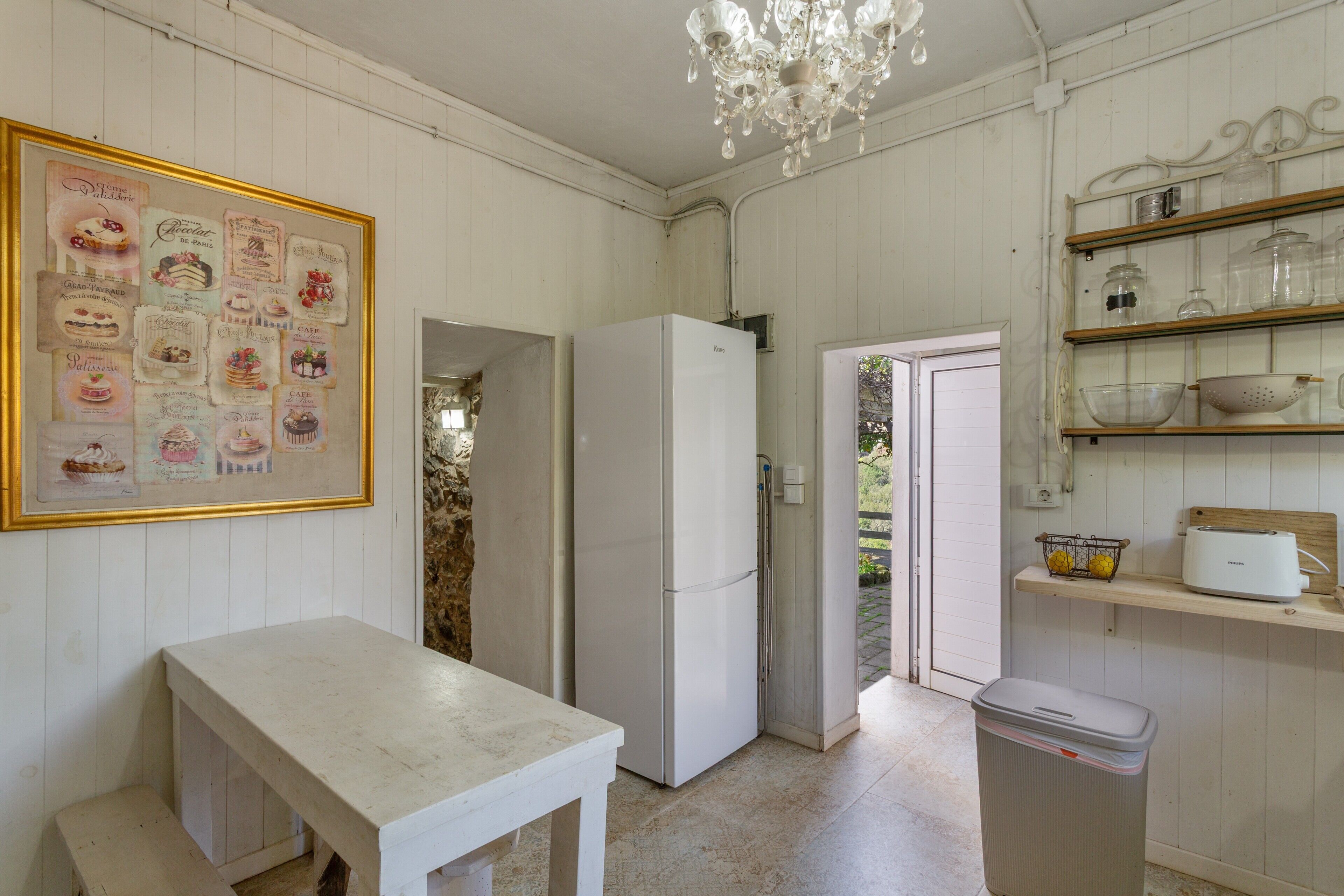 Uma cozinha com geladeira branca, uma mesa e um candelabro.