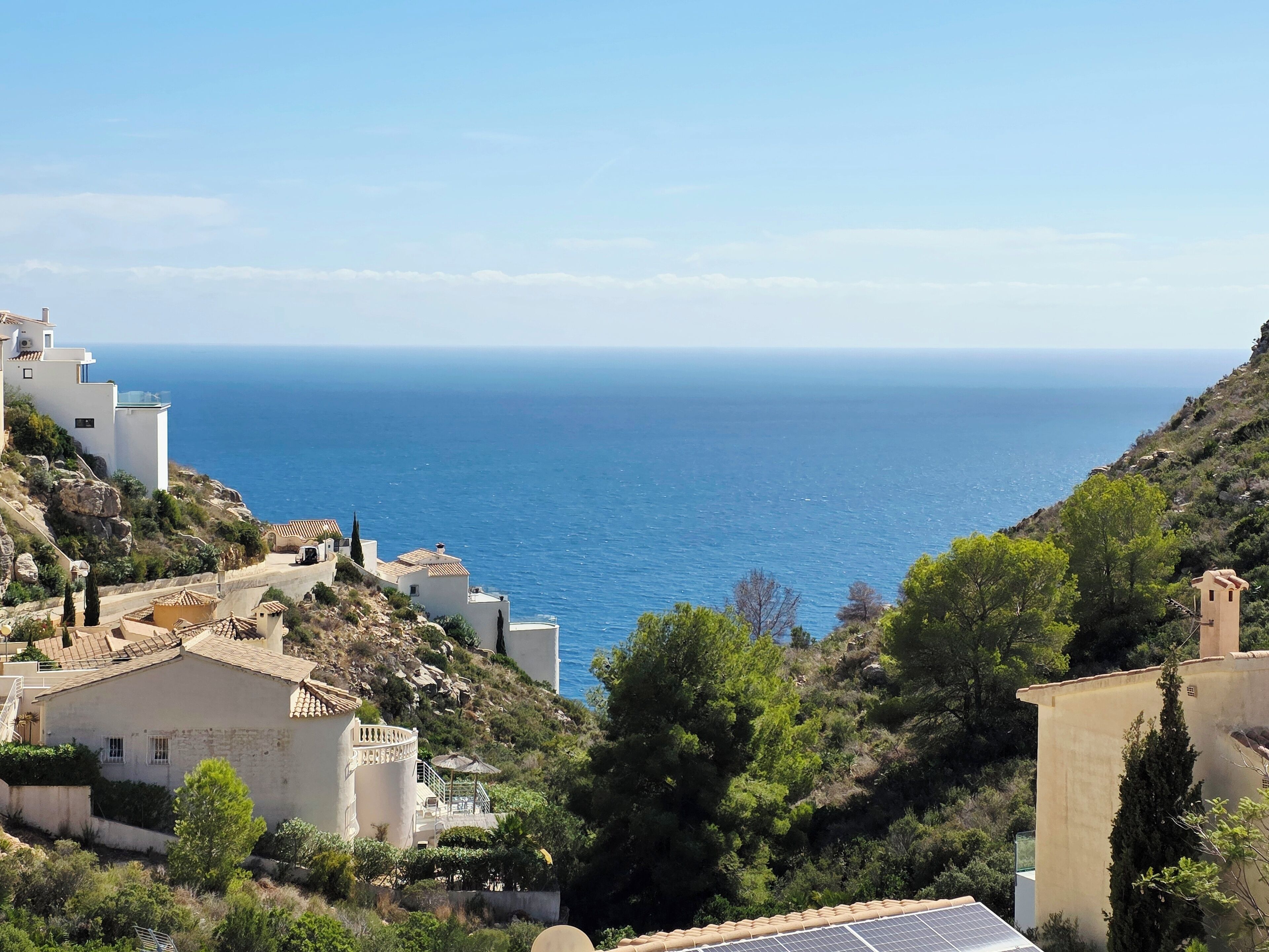 Un village côtier dont les bâtiments donnent sur la mer, caractérisé par des constructions en terrasses et une végétation luxuriante.