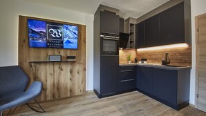 Eine moderne Küche mit dunklen Schränken, einem eingebauten Ofen und einer Wand mit Holzverkleidung.