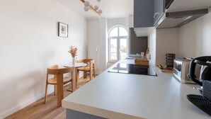 Una cucina moderna con isola centrale, sedie di legno, un tavolo da pranzo e un'ampia finestra.