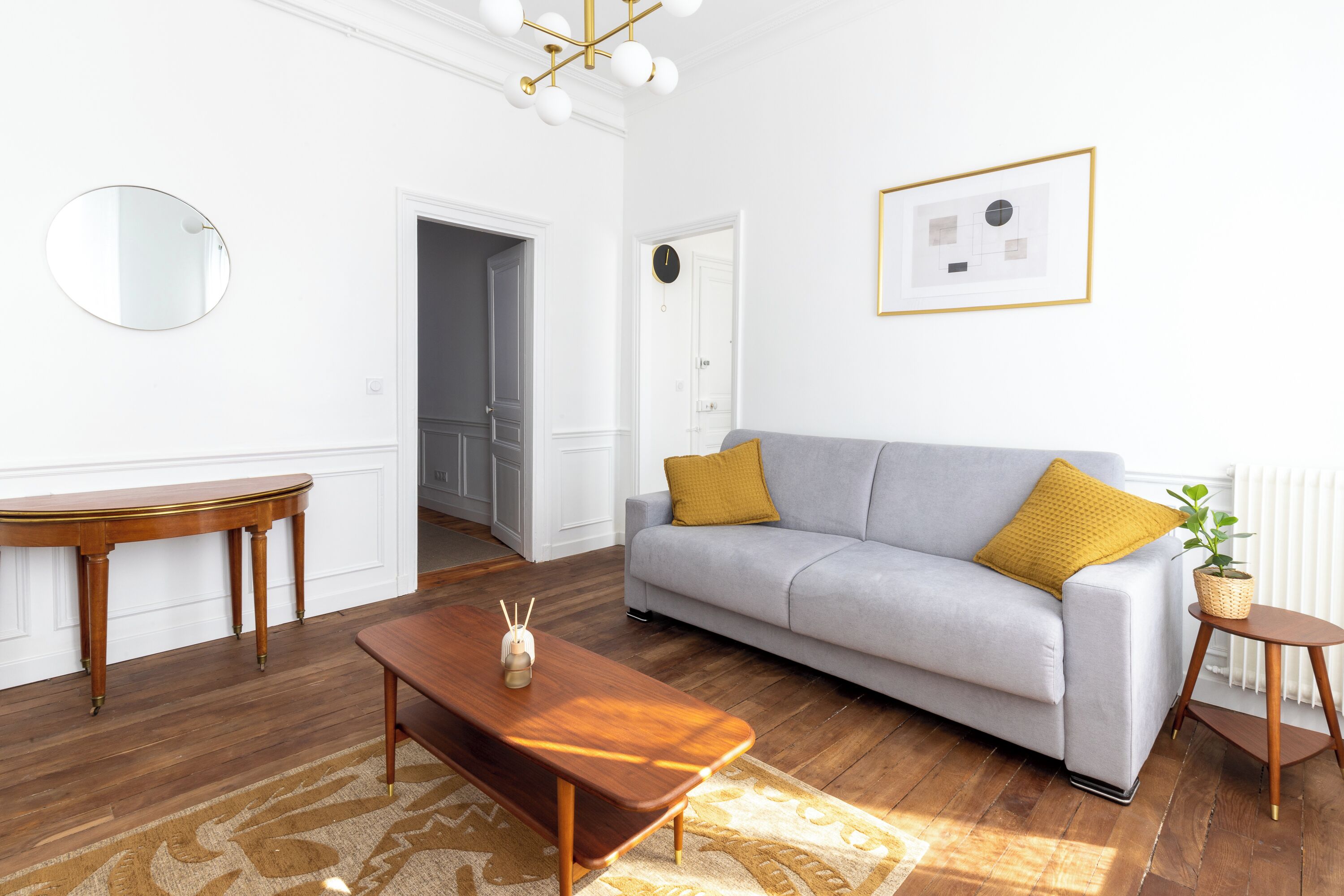 Ein Wohnzimmer mit einer Couch, einem Couchtisch und einem runden Spiegel an der Wand.