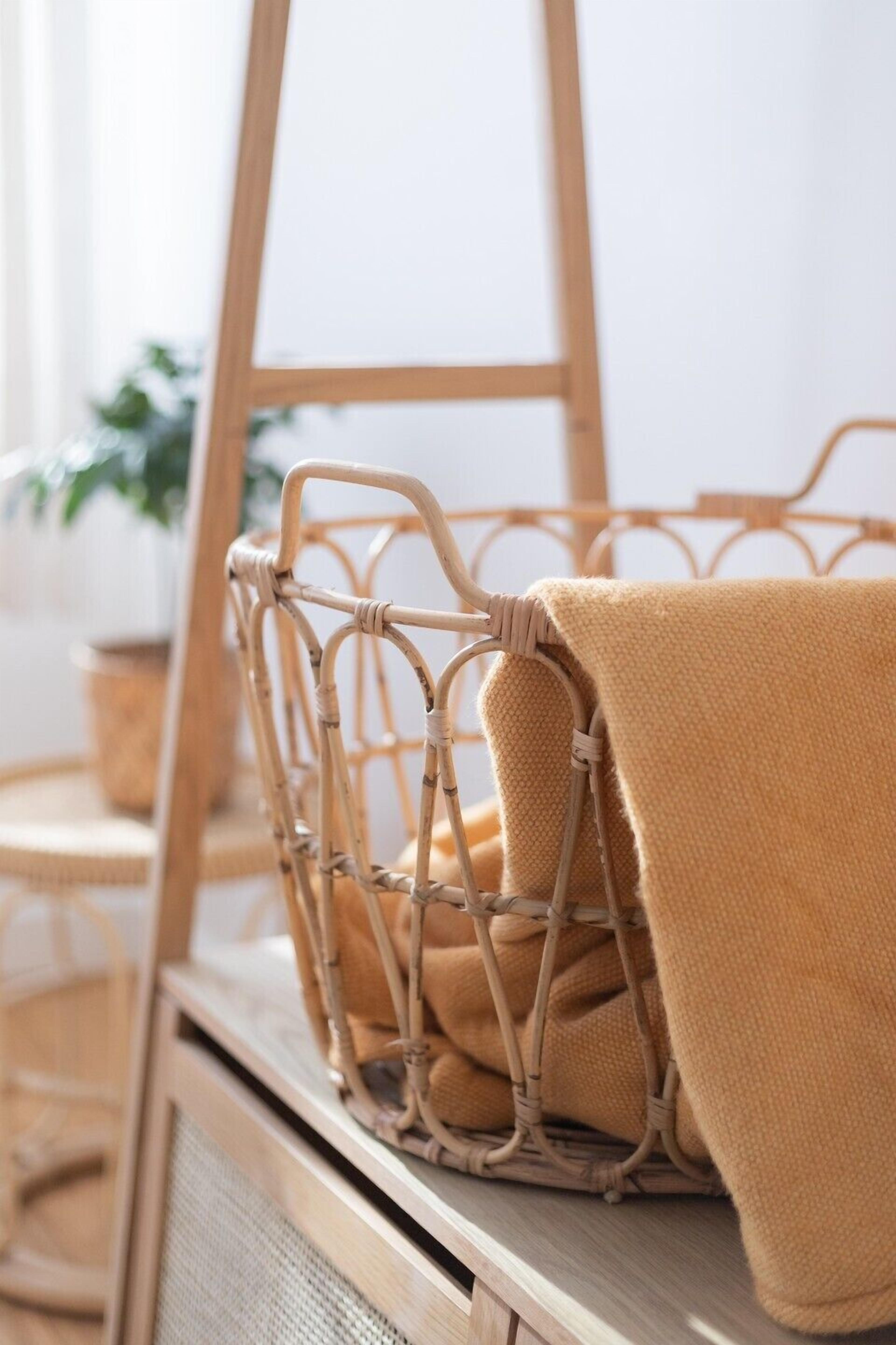 A wicker basket with a beige towel on a wooden surface.