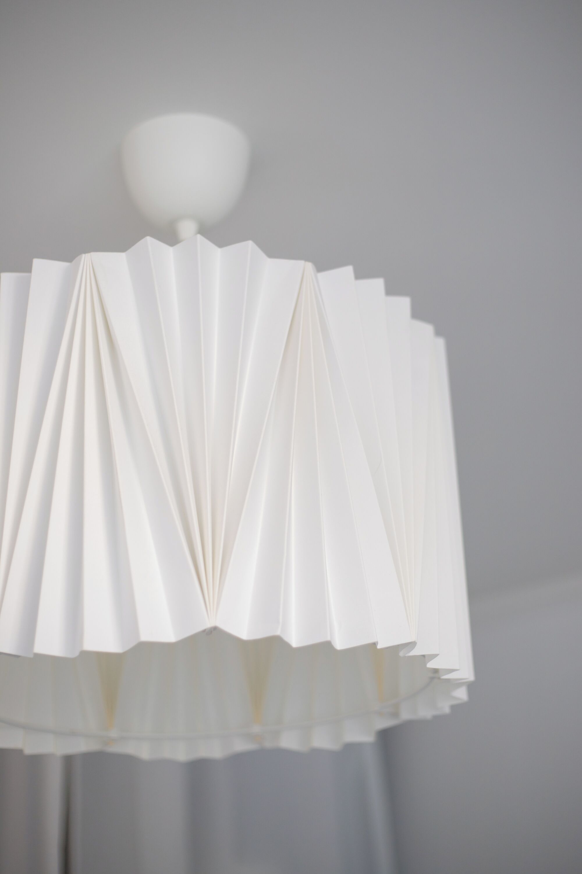 A white, pleated lamp shade with a spherical light fixture.