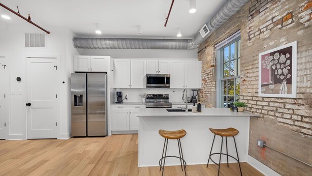 Una cocina moderna con armarios blancos, electrodomésticos de acero inoxidable y una isla grande con taburetes.