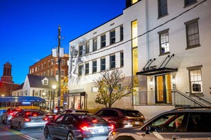 A street view at dusk with a building featuring a large mural, a staircase, and a sign reading "SULLING STREET."