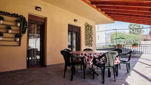 Un patio al aire libre con una mesa, sillas, techo de madera y plantas en macetas.