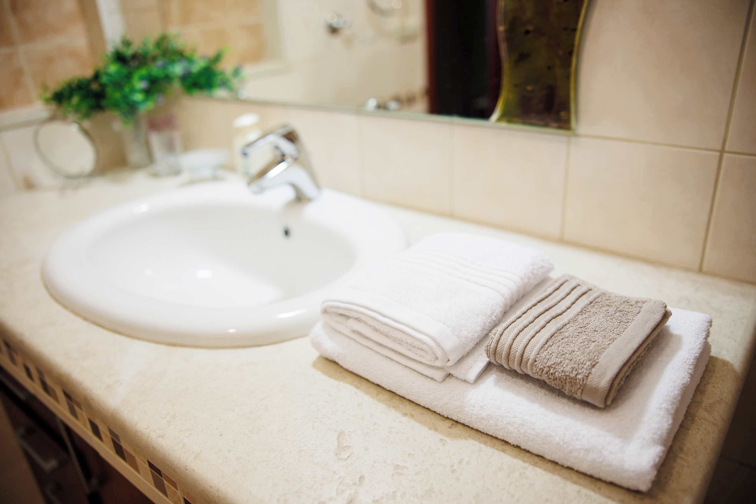 Ein Badezimmer mit Waschbecken, Spiegel und einem Stapel gefalteter Handtücher.