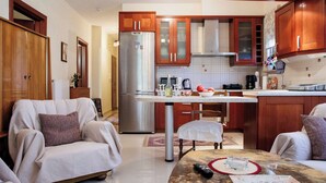 Una cocina moderna con armarios de madera, un refrigerador de acero inoxidable y un comedor con mesa y sillas.