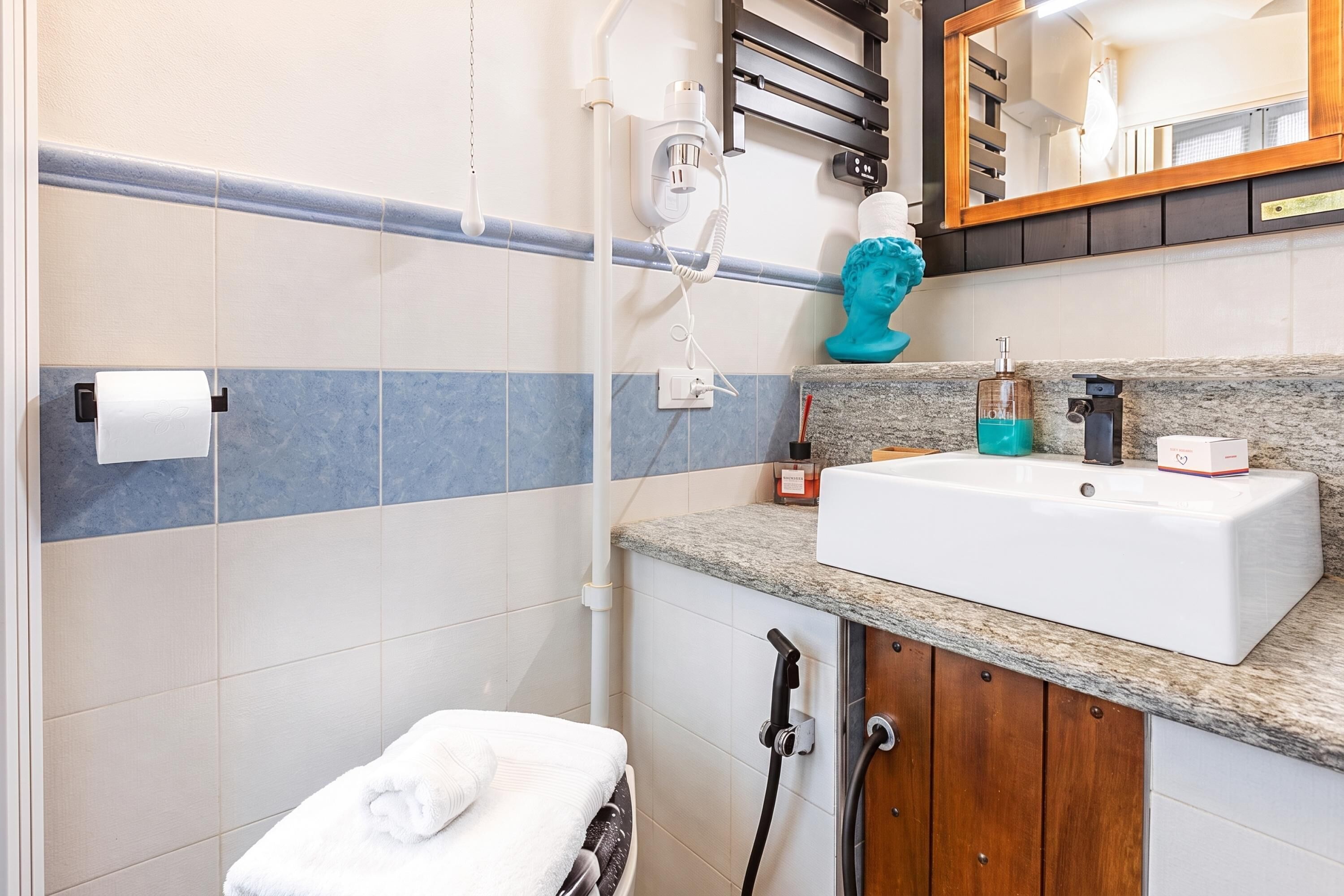 A bathroom with a white sink, a towel, a shower, and a mirror.